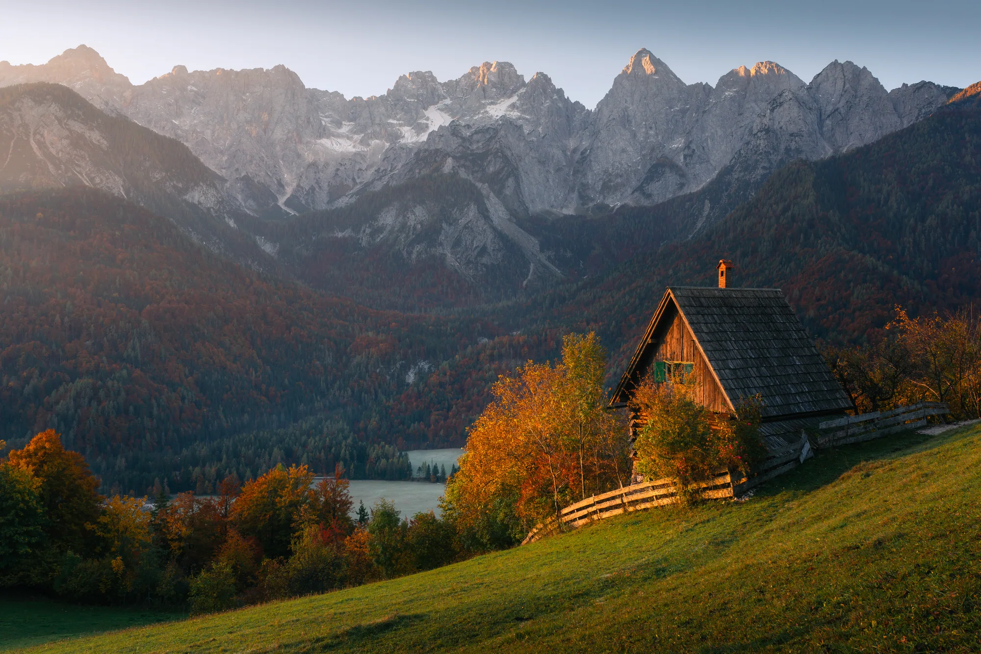 Dřevěná horská chalupa na podzimní stráni pod vápencovými štíty, krajinářská fotografie, fotokurz Slovinsko