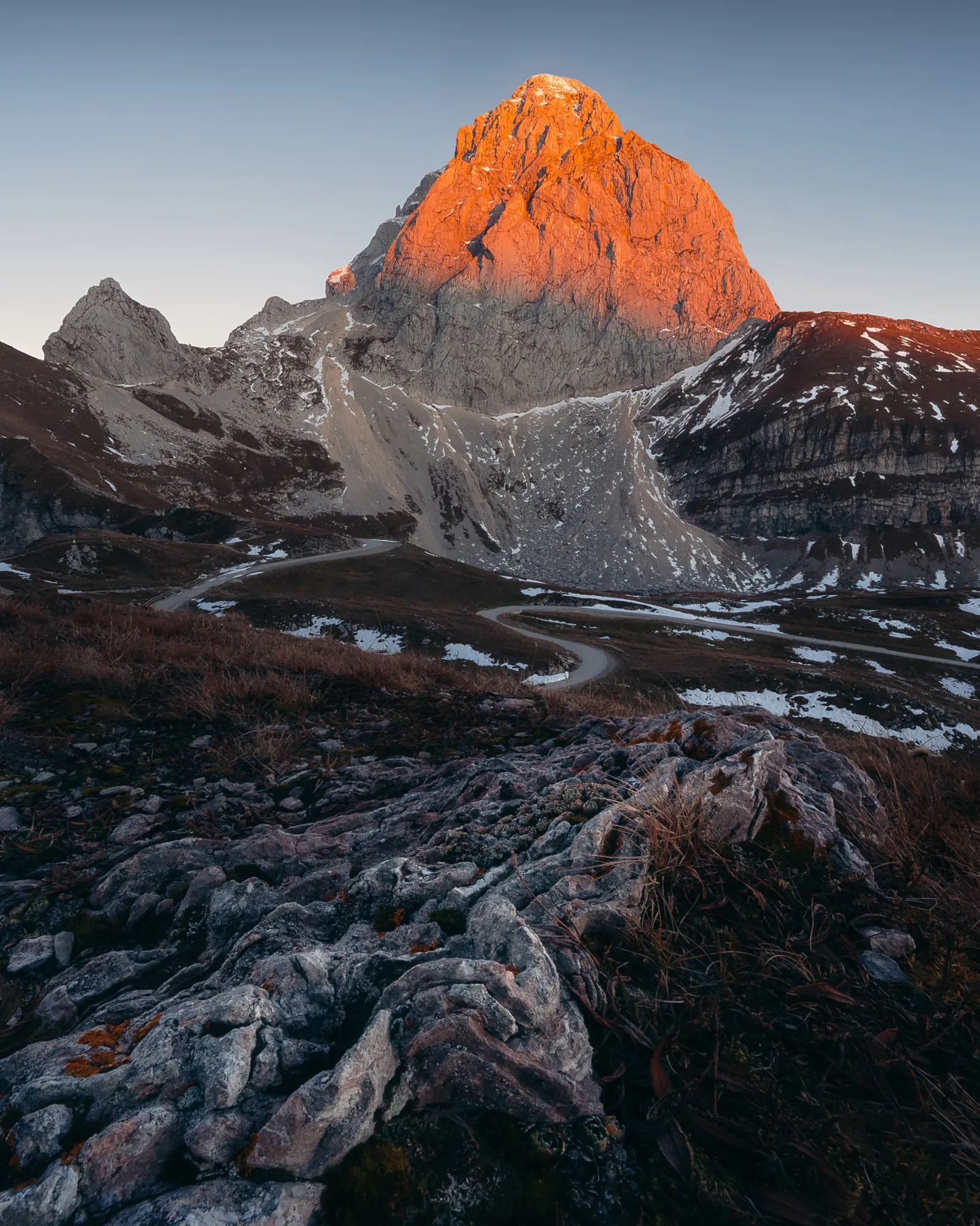 Vrchol Mangart osvícený zapadajícím sluncem nad kamenitým hřebenem, krajinářská fotografie, fotokurz Slovinsko