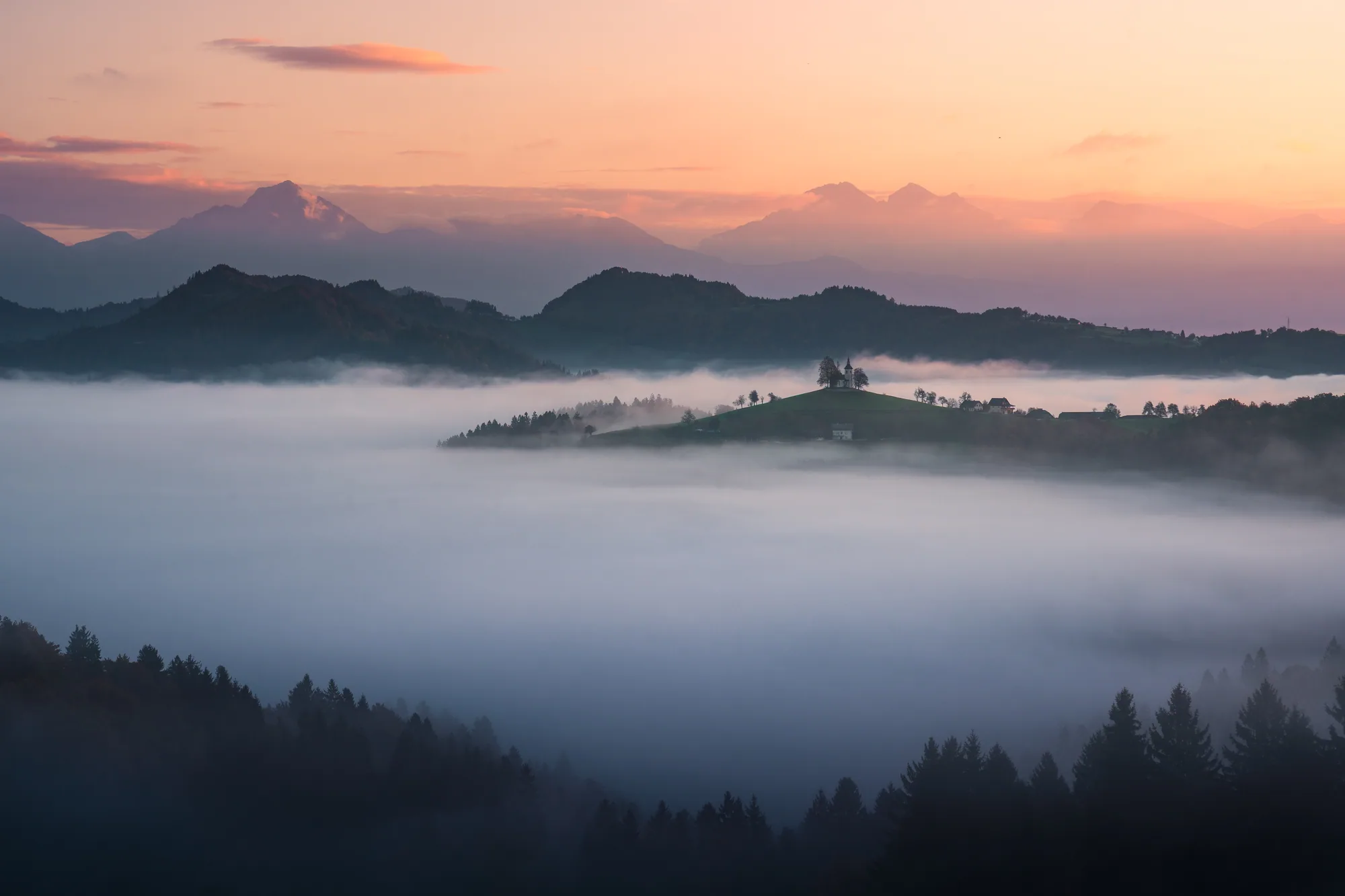 Kopec Sveti Tomaž vystupující z mlhy pod růžovou ranní oblohou, krajinářská fotografie, fotokurz Slovinsko